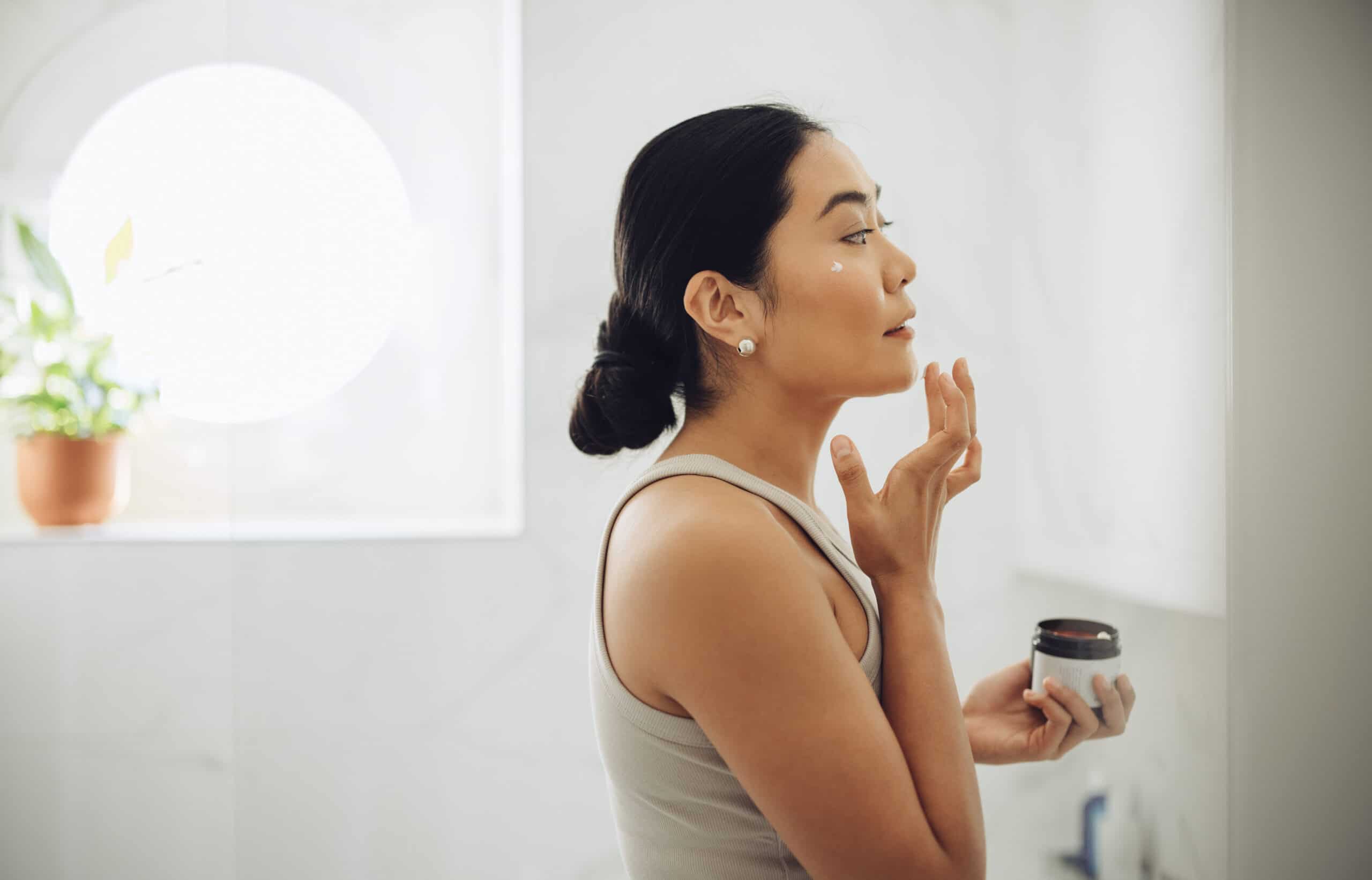 woman applying skincare after reading healthy glowing skin tips