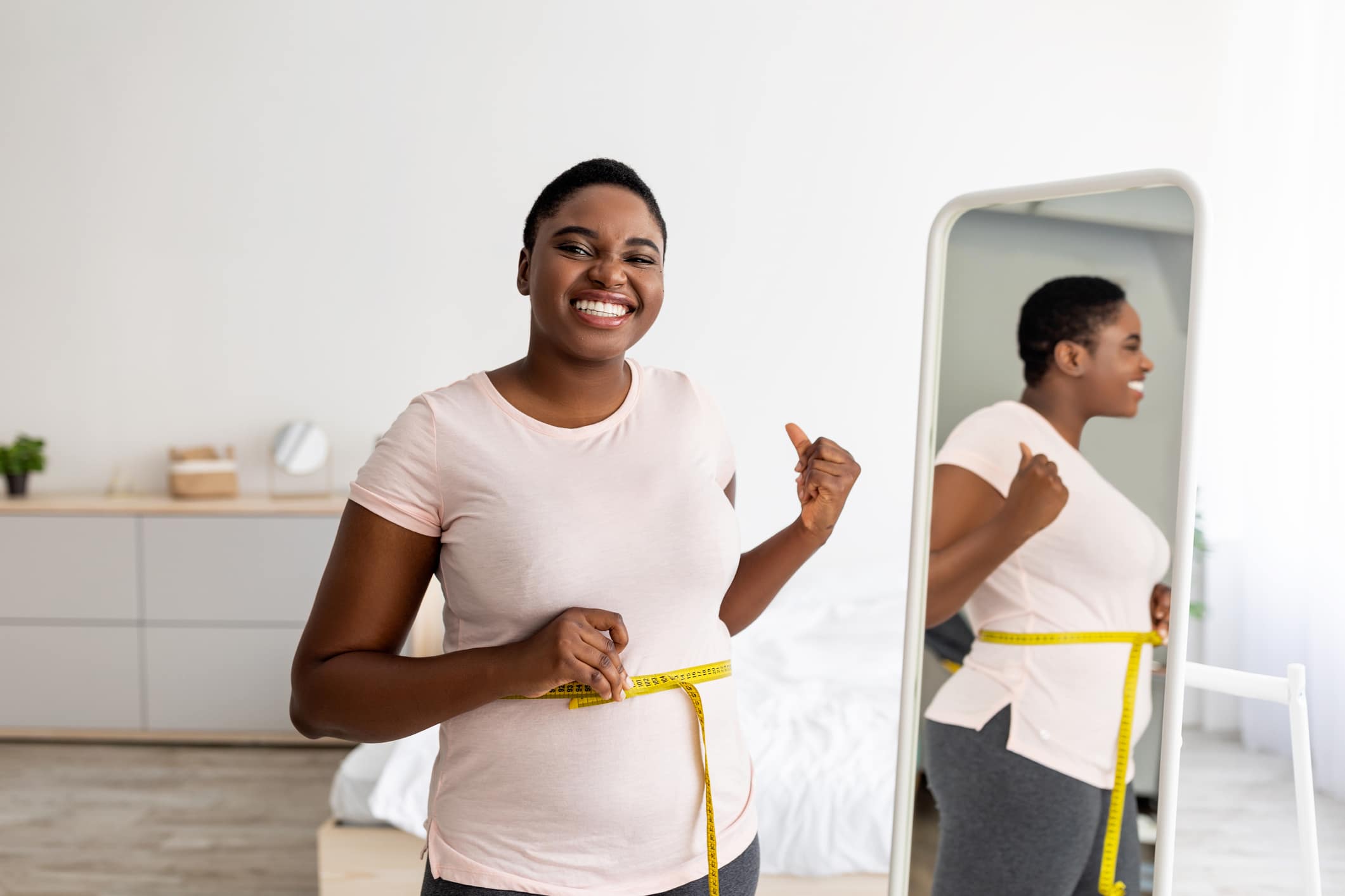 happy woman in the mirror after getting Semaglutide weight loss treatment in Atlanta